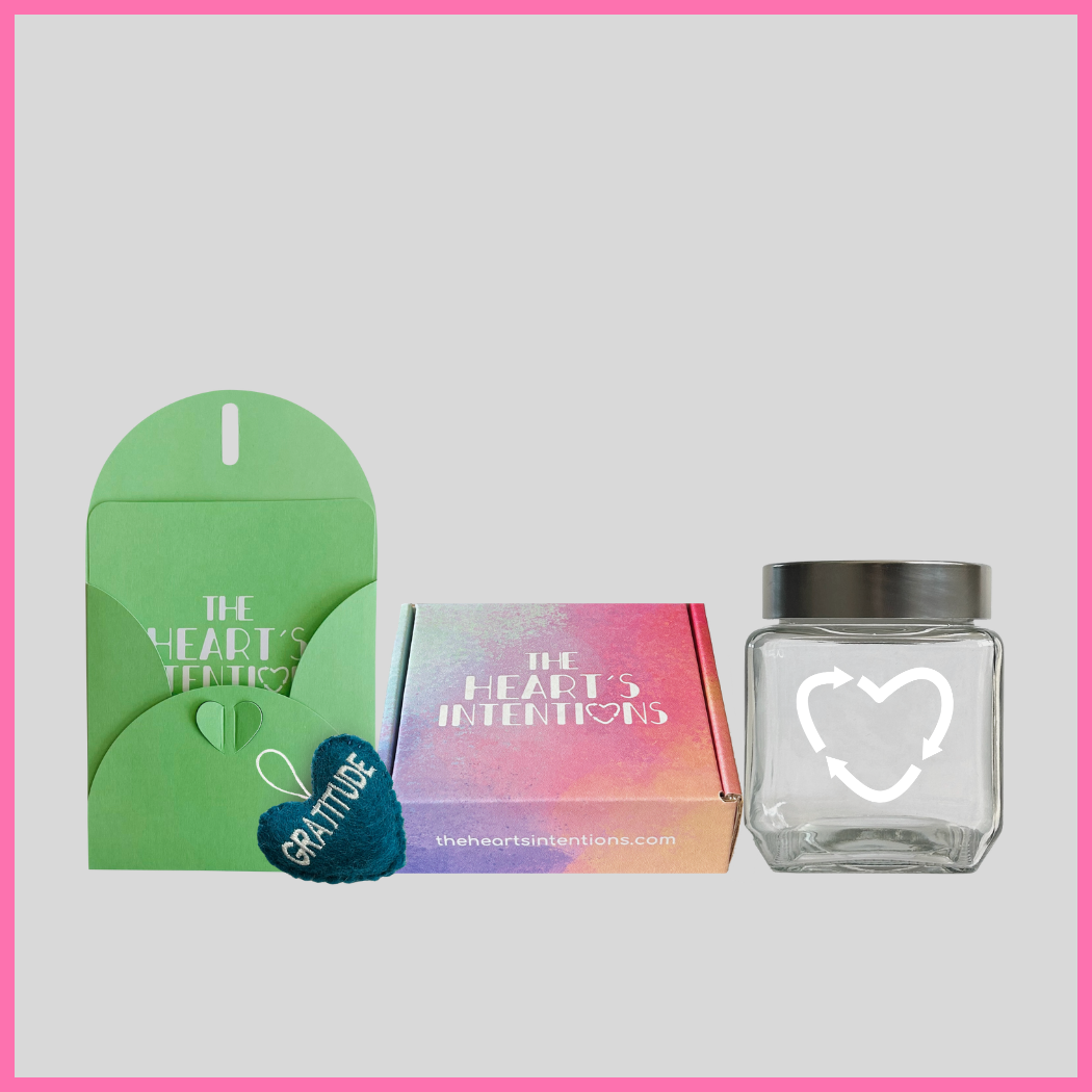 A card and envelope set with a charming heart closure alongside a heart with the word Gratitude on it, beautifully presented next to a heart holder jar with a lid on it to hold your hearts and a The Heart's Intentions gift box, a meaningful way to create lasting memories through a thoughtful gift.