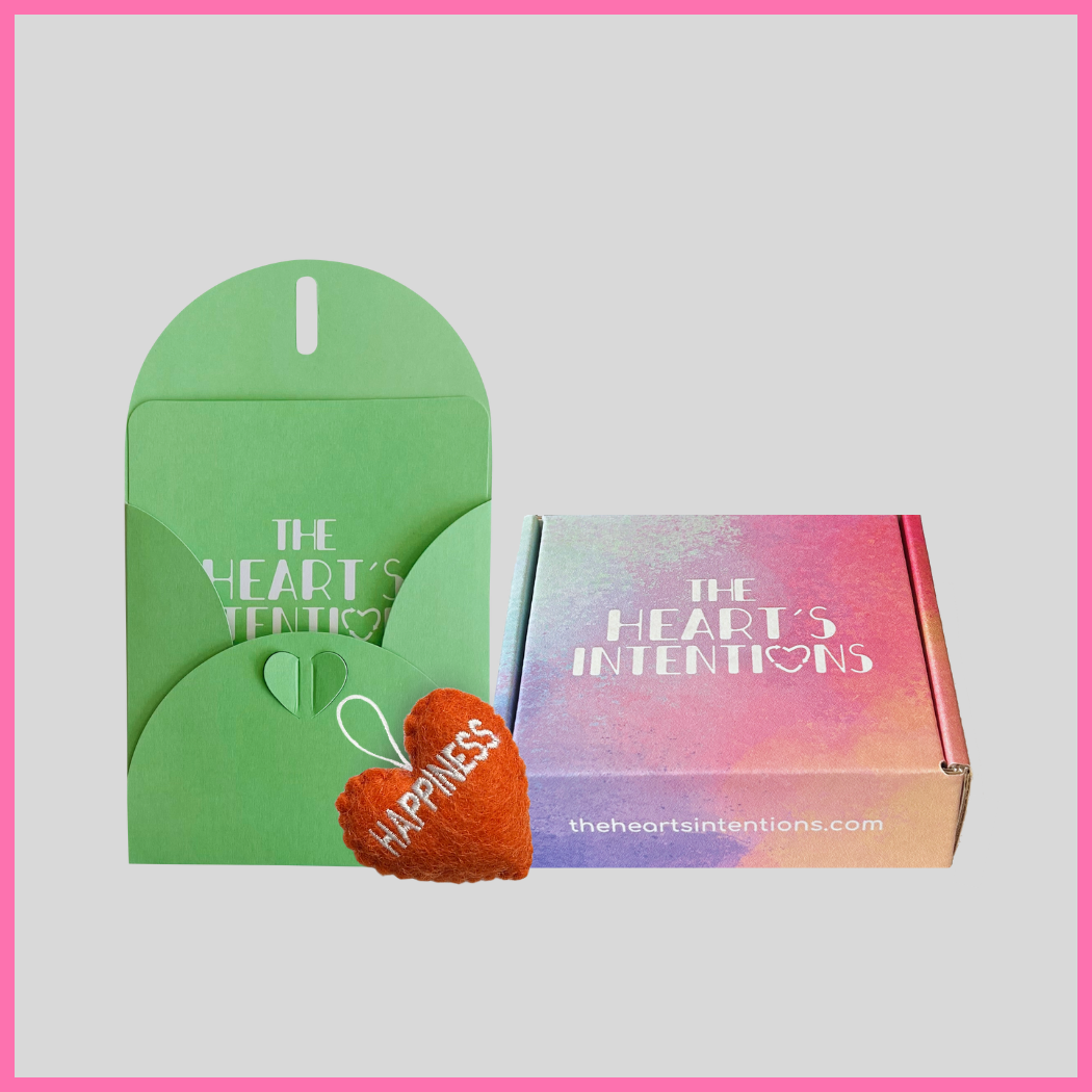 A card and envelope set with a charming heart closure alongside a heart with the word Happiness on it, beautifully presented next to a gift box from The Heart's Intentions, perfect for meaningful and thoughtful gifting. A heartfelt choice for sharing love and connection.