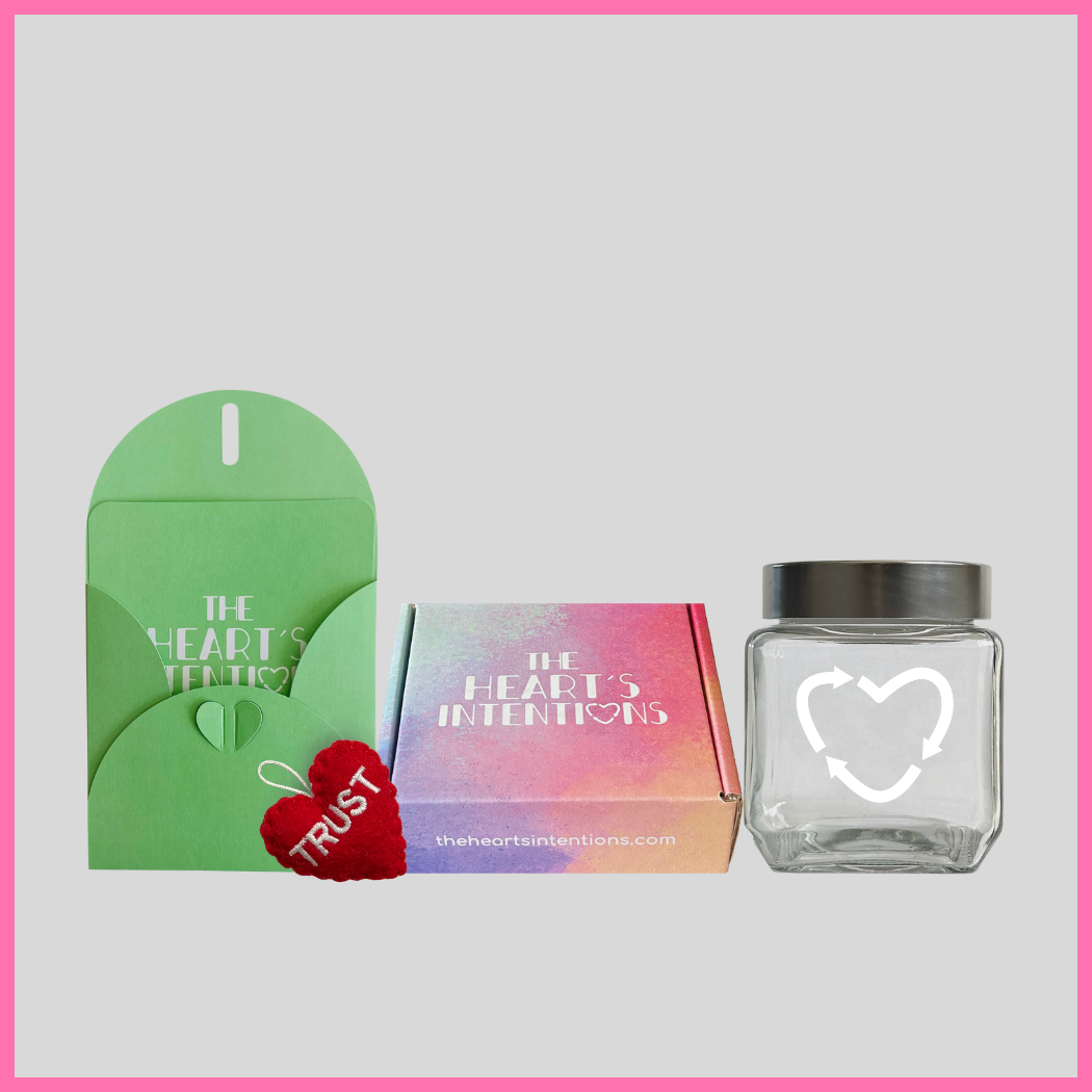 A card and envelope set with a charming heart closure alongside a heart with the word Trust on it, beautifully presented next to a heart holder jar with a lid on it to hold your hearts and a The Heart's Intentions gift box, a meaningful way to create lasting memories through a thoughtful gift.