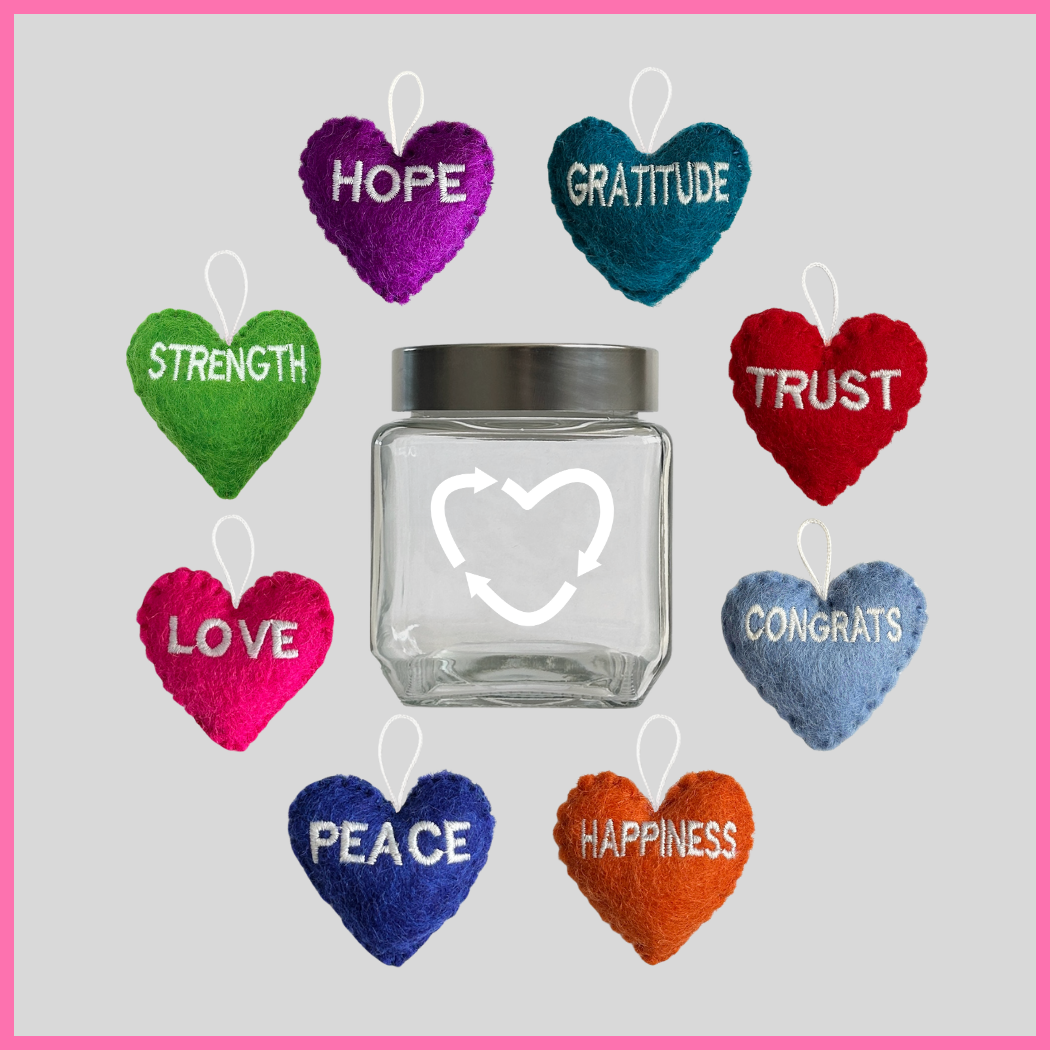 A glass jar filled with eight colorful hearts with words of intention on them like, love, strength, hope, peace, happiness, trust, gratitude, and congrats, part of The Heart's Intentions Heart Holder Bundle, a unique gift designed to touch the heart.