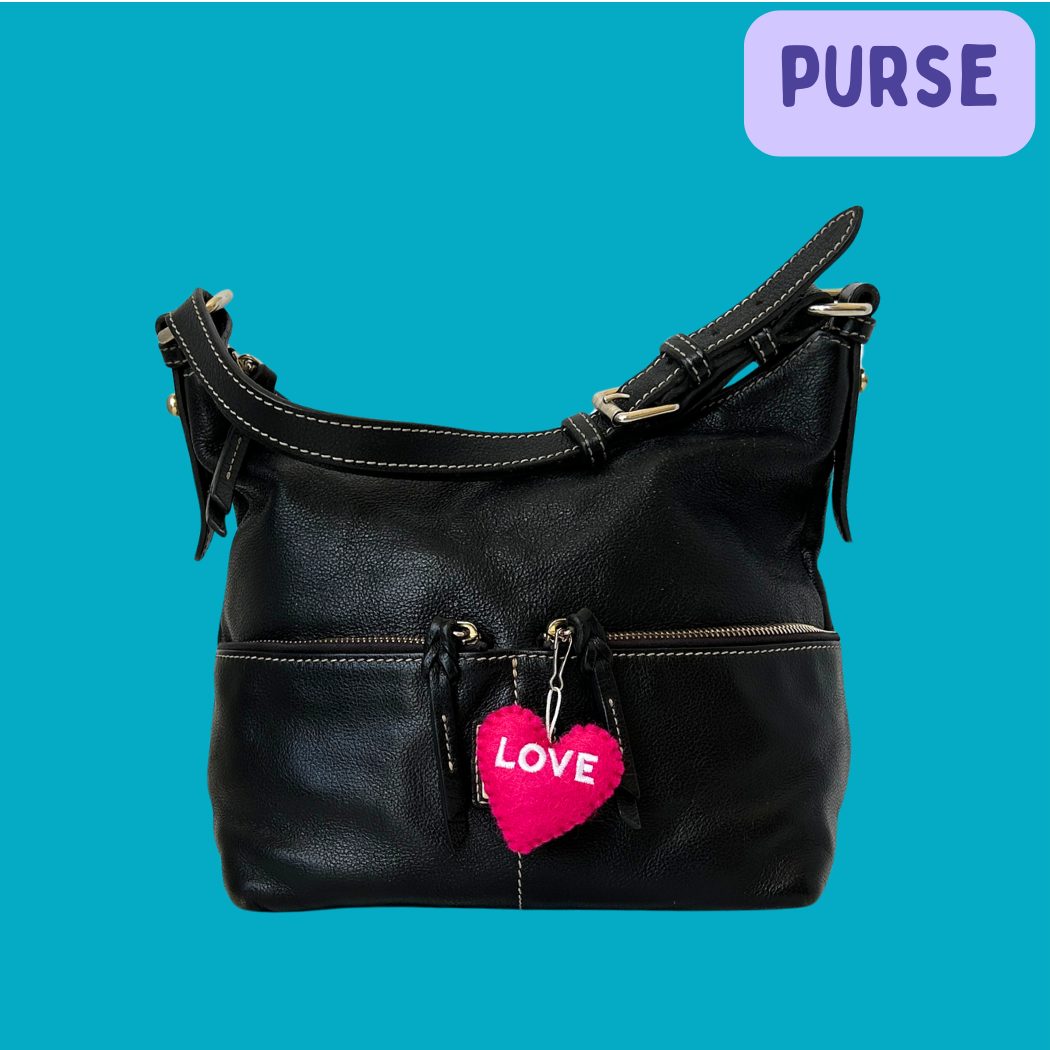 Black purse with pink Love Heart hanging on it.